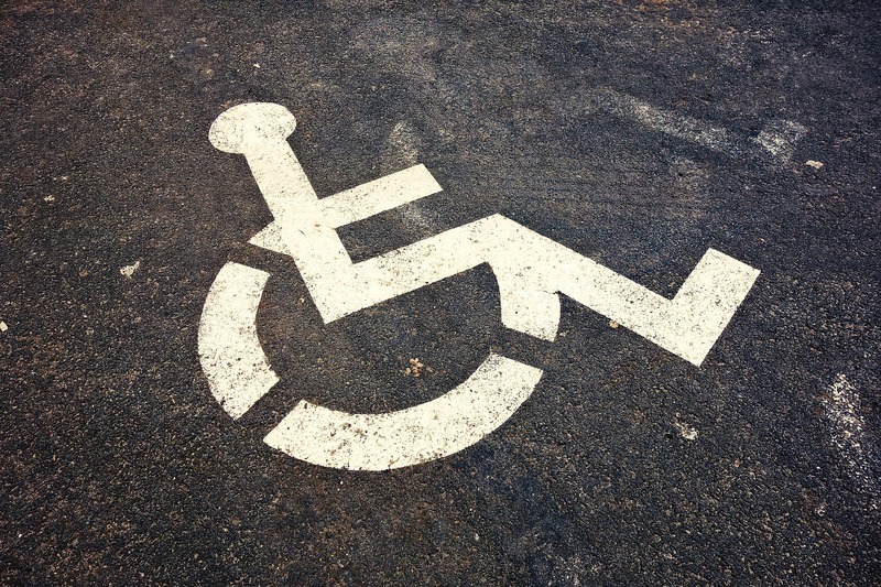 Een handicapstencil op de stoep van een parkeerplaats.